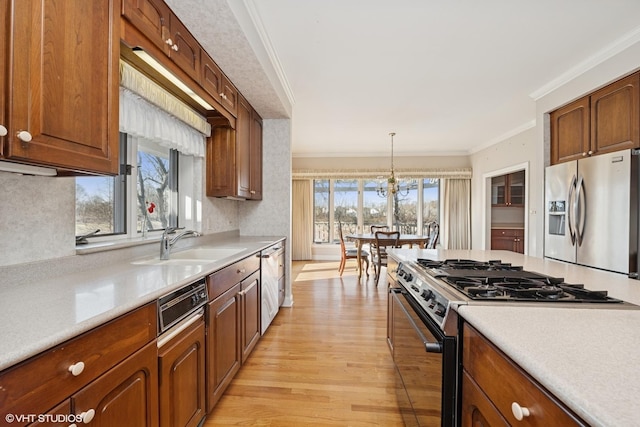 kitchen featuring light countertops, crown molding, appliances with stainless steel finishes, and a sink