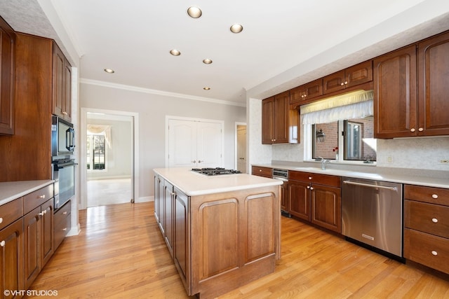 kitchen with light wood-type flooring, a center island, appliances with stainless steel finishes, crown molding, and light countertops