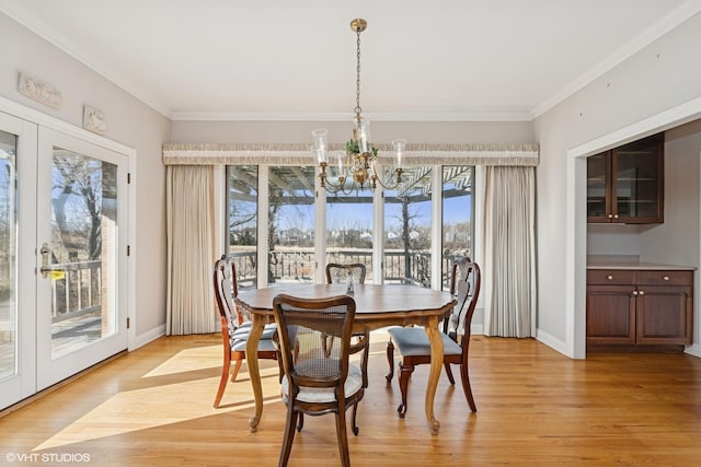 dining space featuring baseboards, light wood-type flooring, an inviting chandelier, and ornamental molding