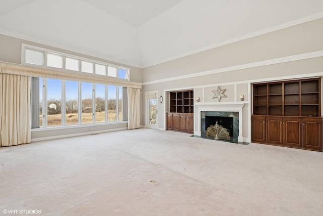 unfurnished living room featuring crown molding, carpet flooring, a high end fireplace, and high vaulted ceiling