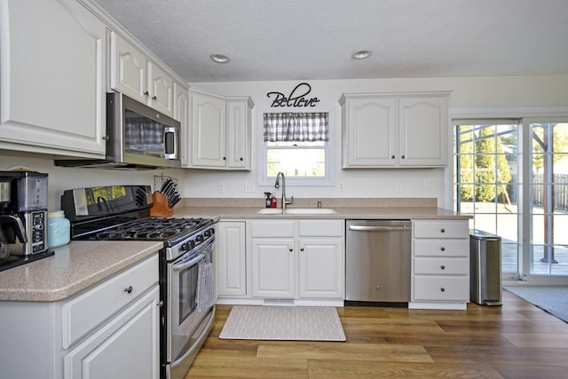 kitchen featuring a sink, light wood-style flooring, white cabinetry, and stainless steel appliances