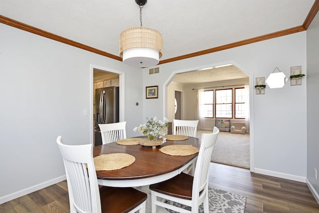 dining area featuring visible vents, arched walkways, dark wood-type flooring, and baseboards