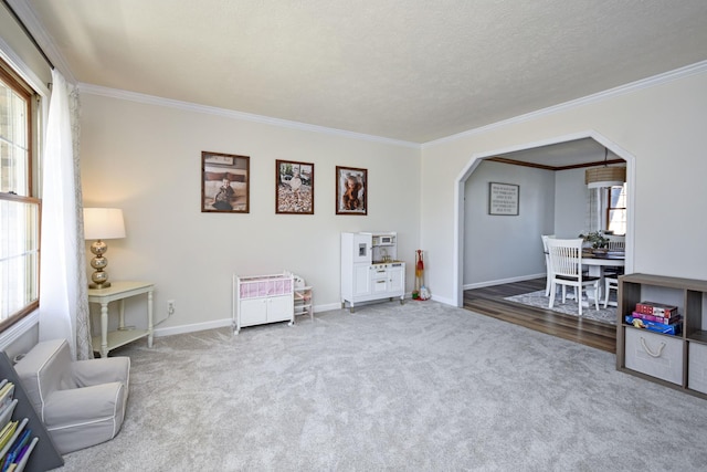 sitting room with arched walkways, carpet flooring, crown molding, and baseboards