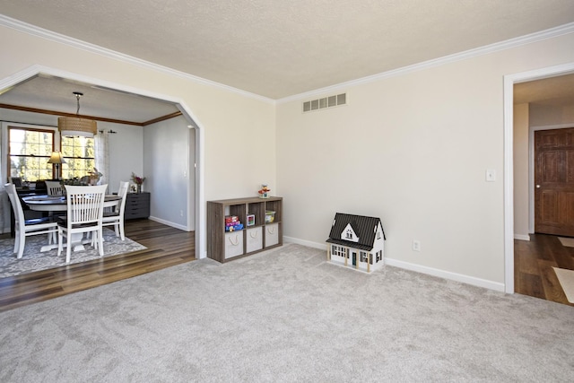 living area with visible vents, arched walkways, carpet flooring, crown molding, and baseboards