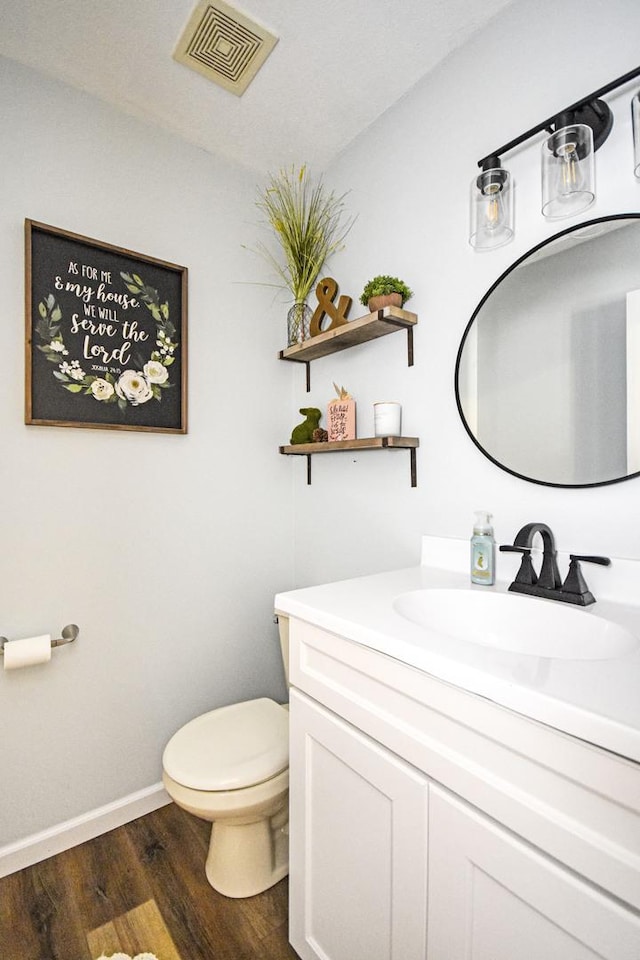 bathroom with vanity, wood finished floors, visible vents, baseboards, and toilet