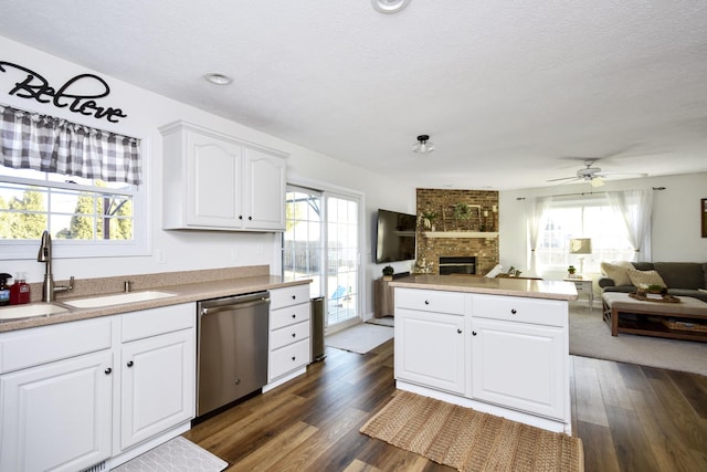 kitchen featuring dark wood-style flooring, a sink, dishwasher, a brick fireplace, and open floor plan