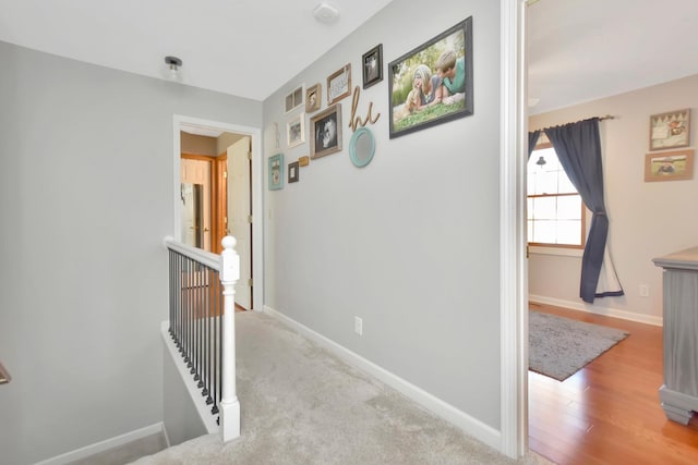 hallway featuring baseboards, an upstairs landing, and wood finished floors