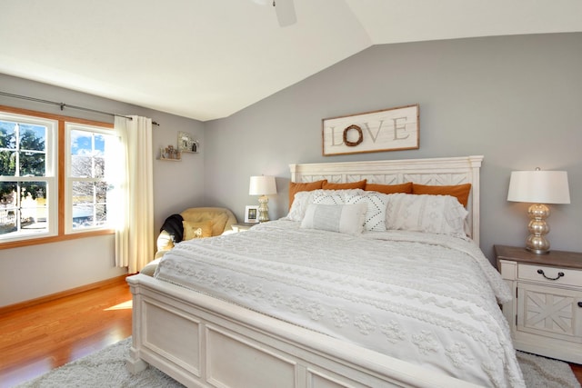 bedroom with baseboards, a ceiling fan, light wood-style floors, and lofted ceiling