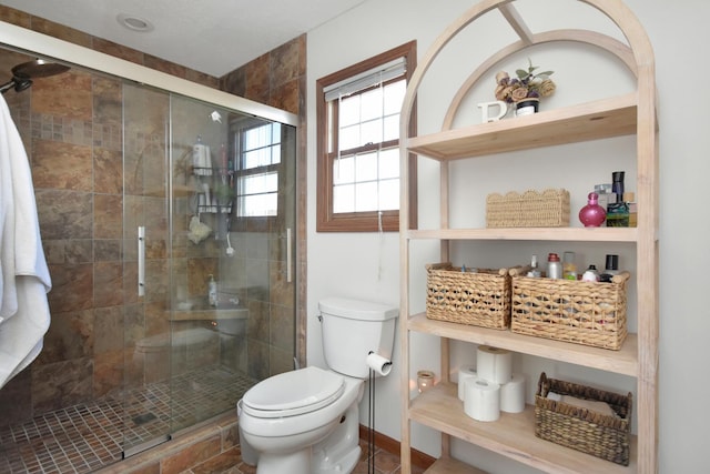 bathroom with toilet, baseboards, and a stall shower