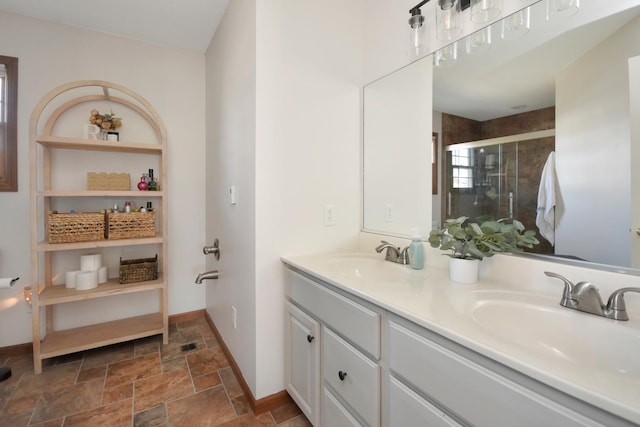 full bath featuring double vanity, stone finish floor, a stall shower, and a sink