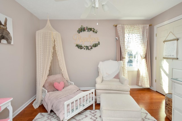 living area with light wood finished floors, a ceiling fan, and baseboards