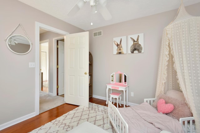 bedroom featuring visible vents, a ceiling fan, baseboards, and wood finished floors