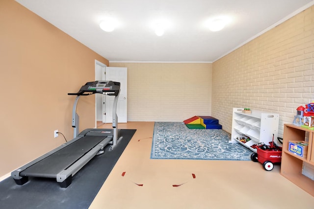 workout area with crown molding and brick wall