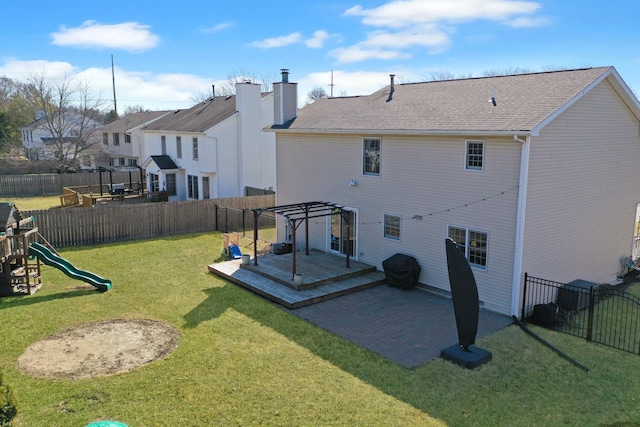 back of property featuring a lawn, a wooden deck, a playground, and a fenced backyard