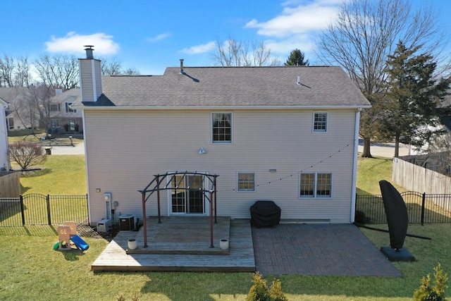 rear view of house featuring a wooden deck, a yard, fence, and a chimney