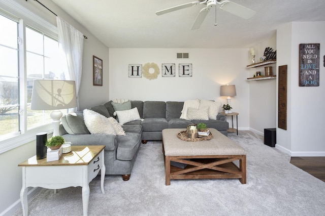 living area featuring plenty of natural light, baseboards, visible vents, and ceiling fan