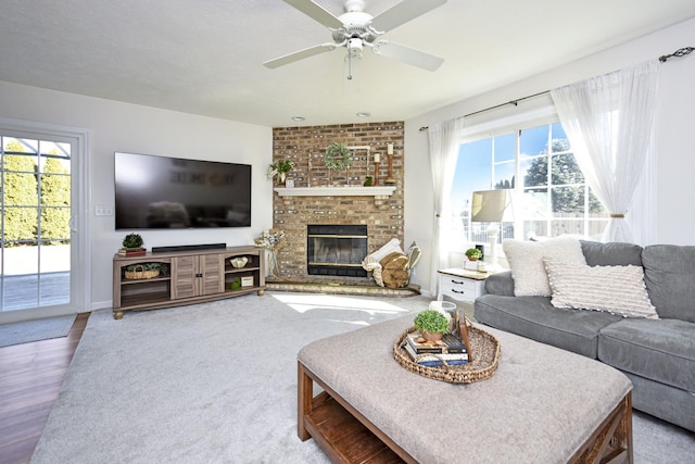 living area featuring a brick fireplace, a healthy amount of sunlight, and ceiling fan