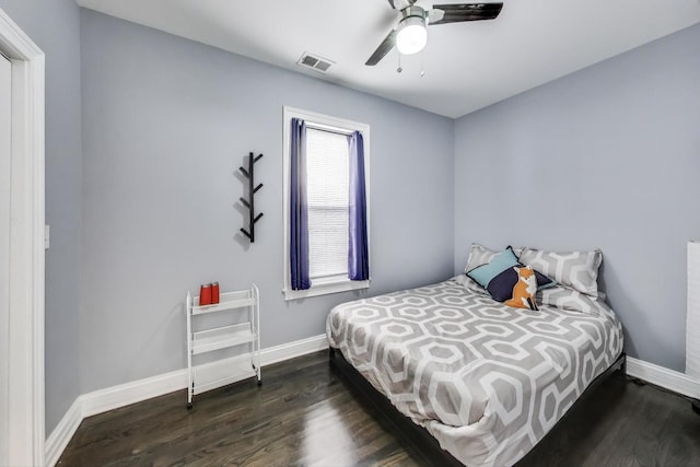 bedroom featuring ceiling fan, visible vents, baseboards, and wood finished floors