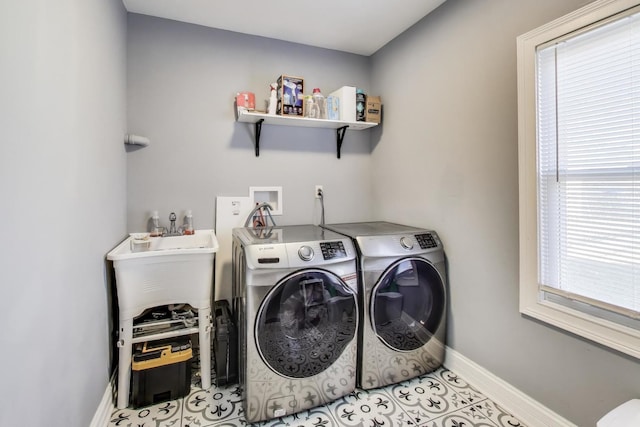 clothes washing area featuring light tile patterned floors, baseboards, washing machine and dryer, and laundry area