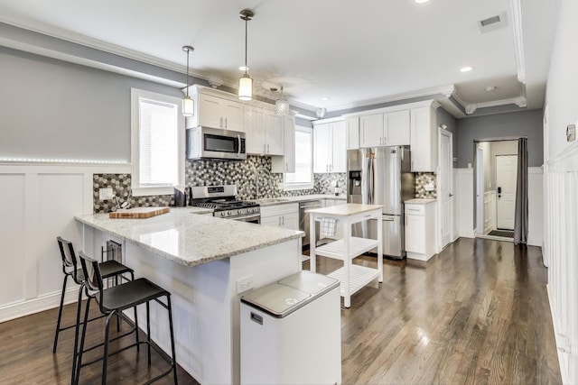 kitchen featuring visible vents, white cabinetry, a peninsula, appliances with stainless steel finishes, and a kitchen bar