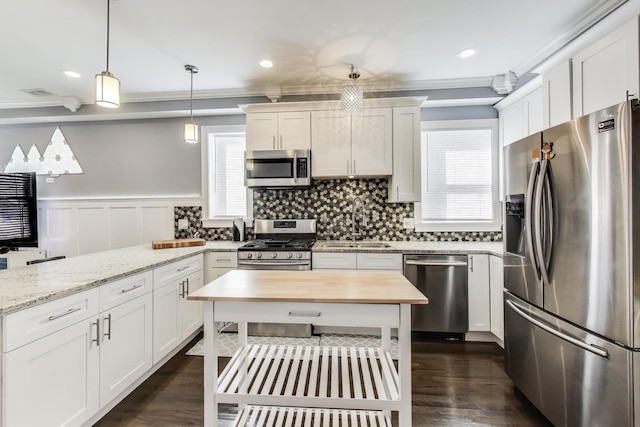 kitchen with a peninsula, a sink, appliances with stainless steel finishes, white cabinetry, and tasteful backsplash