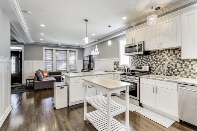 kitchen featuring a sink, a peninsula, white cabinets, and stainless steel appliances