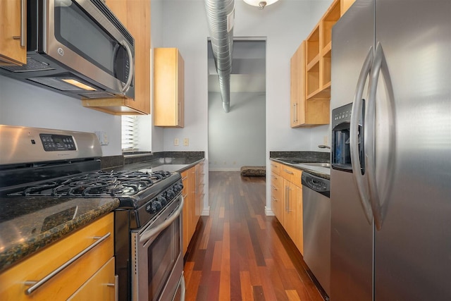 kitchen with dark stone countertops, dark wood-style floors, baseboards, and stainless steel appliances