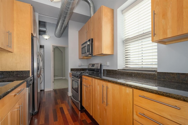 kitchen featuring dark stone countertops, appliances with stainless steel finishes, dark wood-type flooring, and brown cabinets