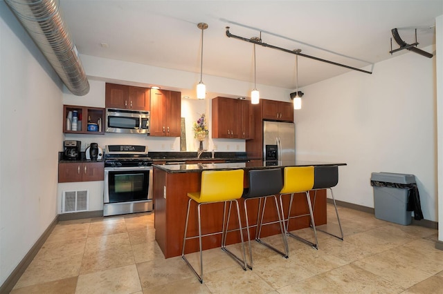 kitchen with visible vents, appliances with stainless steel finishes, a kitchen bar, dark countertops, and a center island