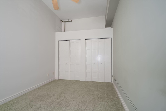 unfurnished bedroom featuring baseboards, carpet floors, two closets, and ceiling fan