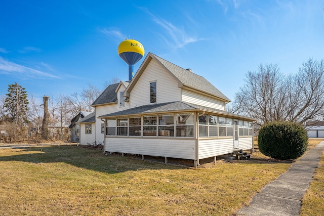 back of property featuring a lawn, roof with shingles, and a sunroom