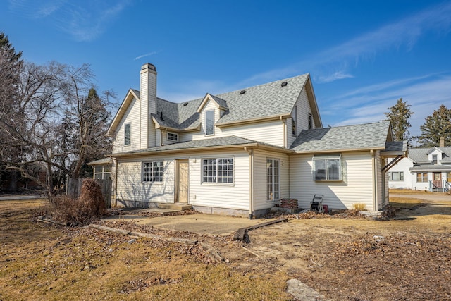 back of property with entry steps, a chimney, and a shingled roof