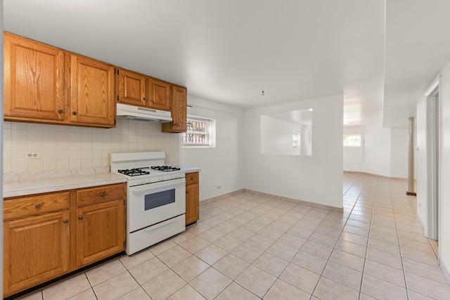 4556 N Newcastle Ave, Harwood Heights, IL 60706 - kitchen featuring white gas stove, under cabinet range hood, light countertops, backsplash, and light tile patterned flooring