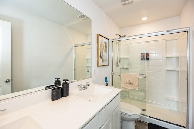 full bathroom featuring double vanity, recessed lighting, a stall shower, a sink, and toilet