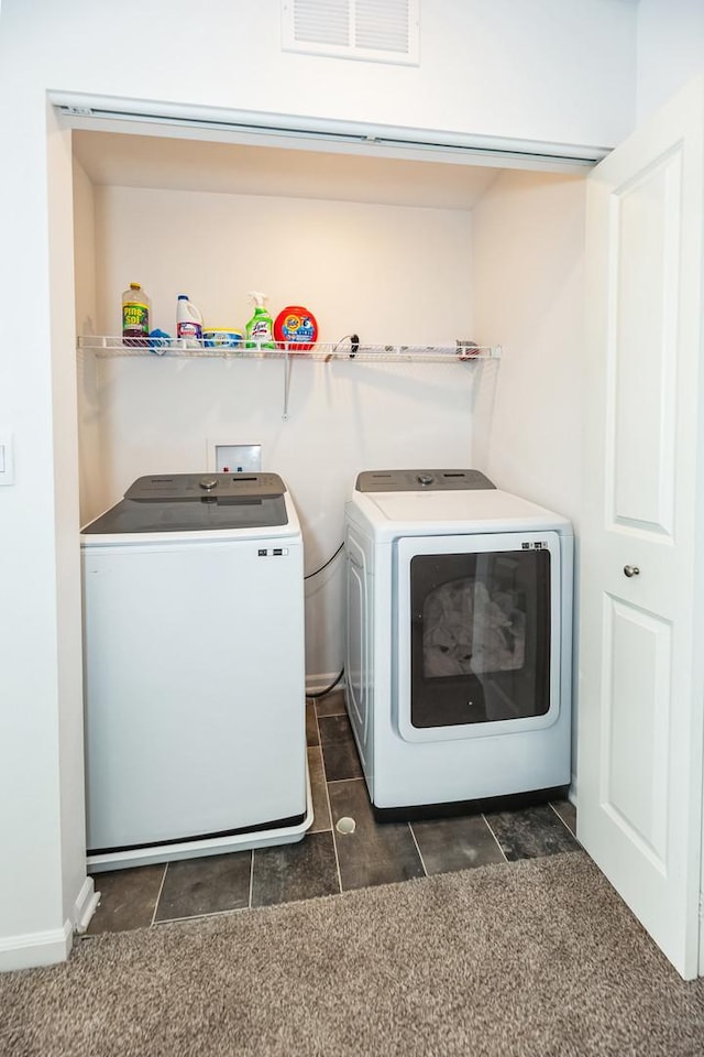 washroom featuring laundry area, washing machine and dryer, dark carpet, and visible vents