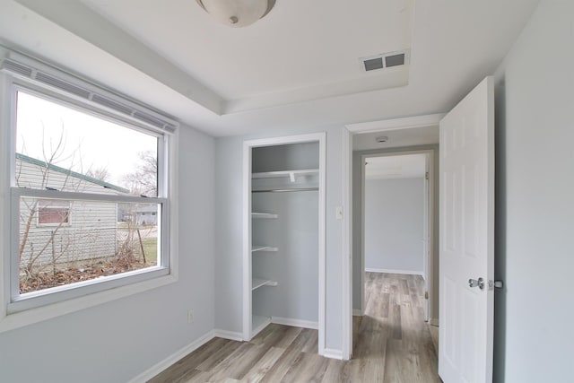 unfurnished bedroom featuring light wood finished floors, visible vents, a closet, and baseboards