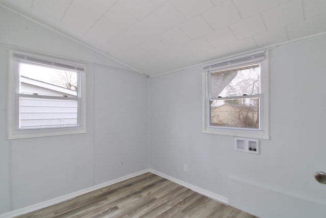unfurnished room featuring lofted ceiling, wood finished floors, baseboards, and a wealth of natural light