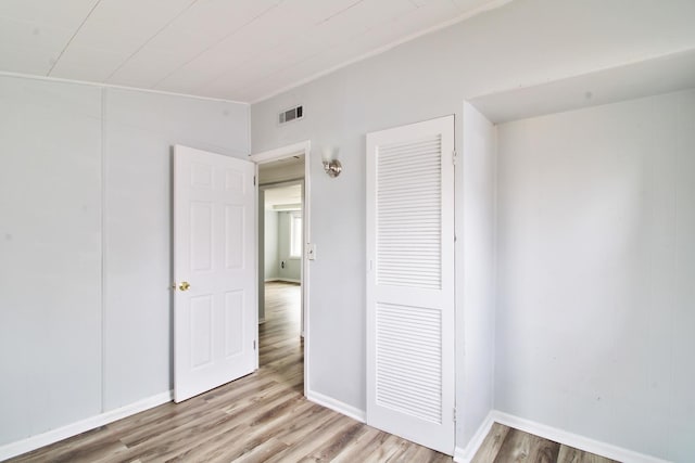 unfurnished bedroom featuring wood finished floors, visible vents, and a closet