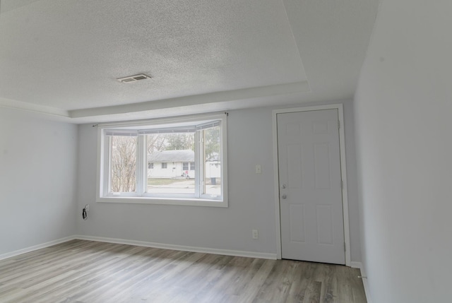 empty room featuring baseboards, wood finished floors, visible vents, and a textured ceiling