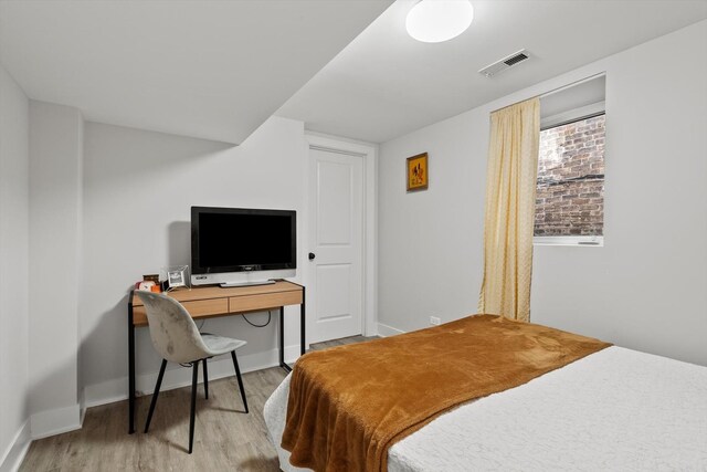 bedroom featuring visible vents, baseboards, and wood finished floors