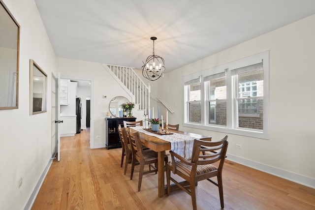 dining area with stairway, light wood-style floors, baseboards, and a chandelier