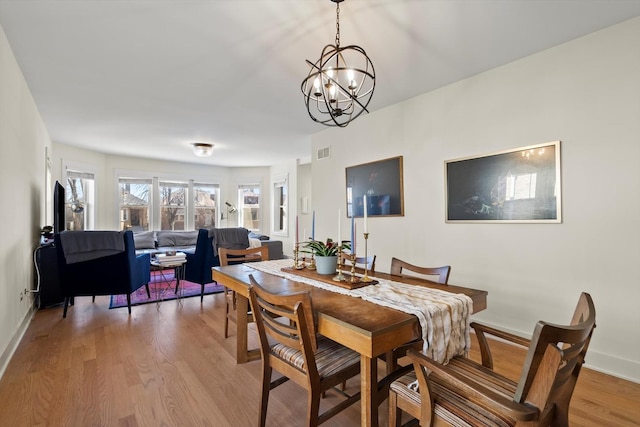 dining room featuring light wood-style flooring, baseboards, visible vents, and a chandelier