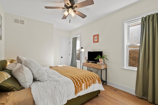 bedroom featuring visible vents, a ceiling fan, baseboards, and wood finished floors