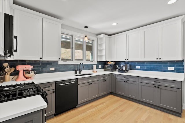 kitchen with gray cabinetry, a sink, light countertops, dishwasher, and light wood-type flooring