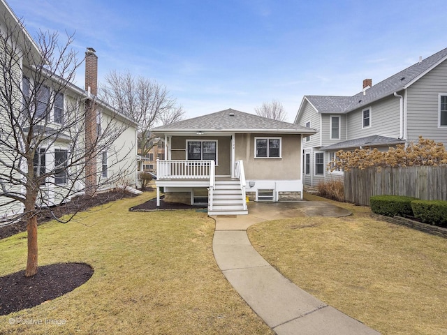 view of front of home featuring stucco siding, roof with shingles, a front yard, and fence