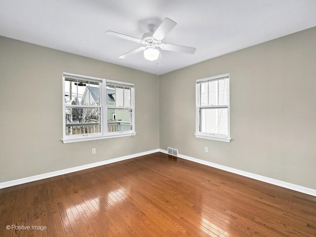 empty room featuring visible vents, ceiling fan, baseboards, and hardwood / wood-style flooring