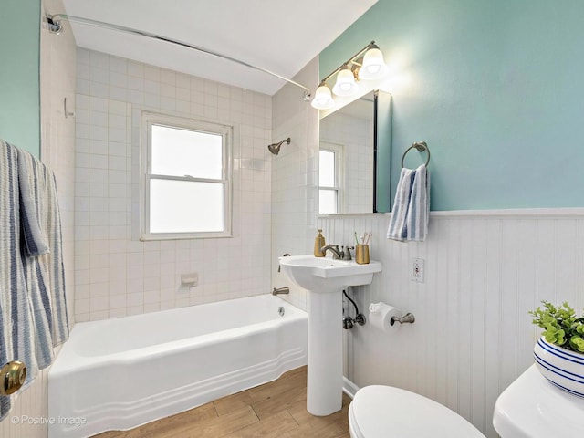 bathroom with a wainscoted wall, toilet, a healthy amount of sunlight, and wood finished floors