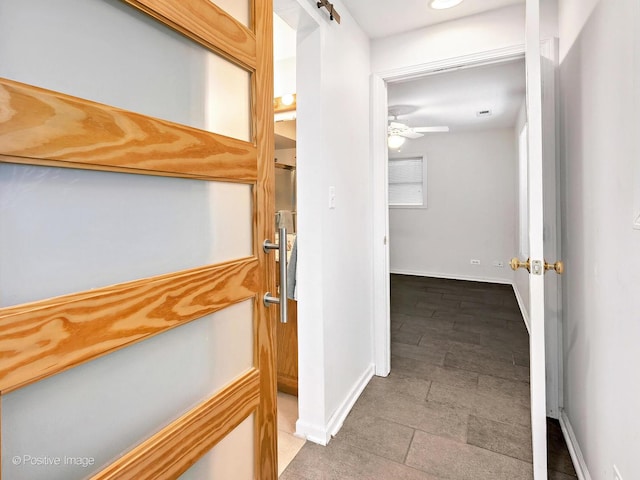 hallway featuring a barn door and baseboards