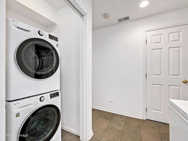 laundry area featuring visible vents, recessed lighting, stacked washer and clothes dryer, and baseboards