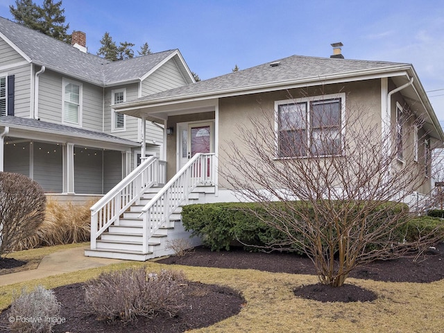 view of front of home featuring stucco siding, roof with shingles, and a chimney